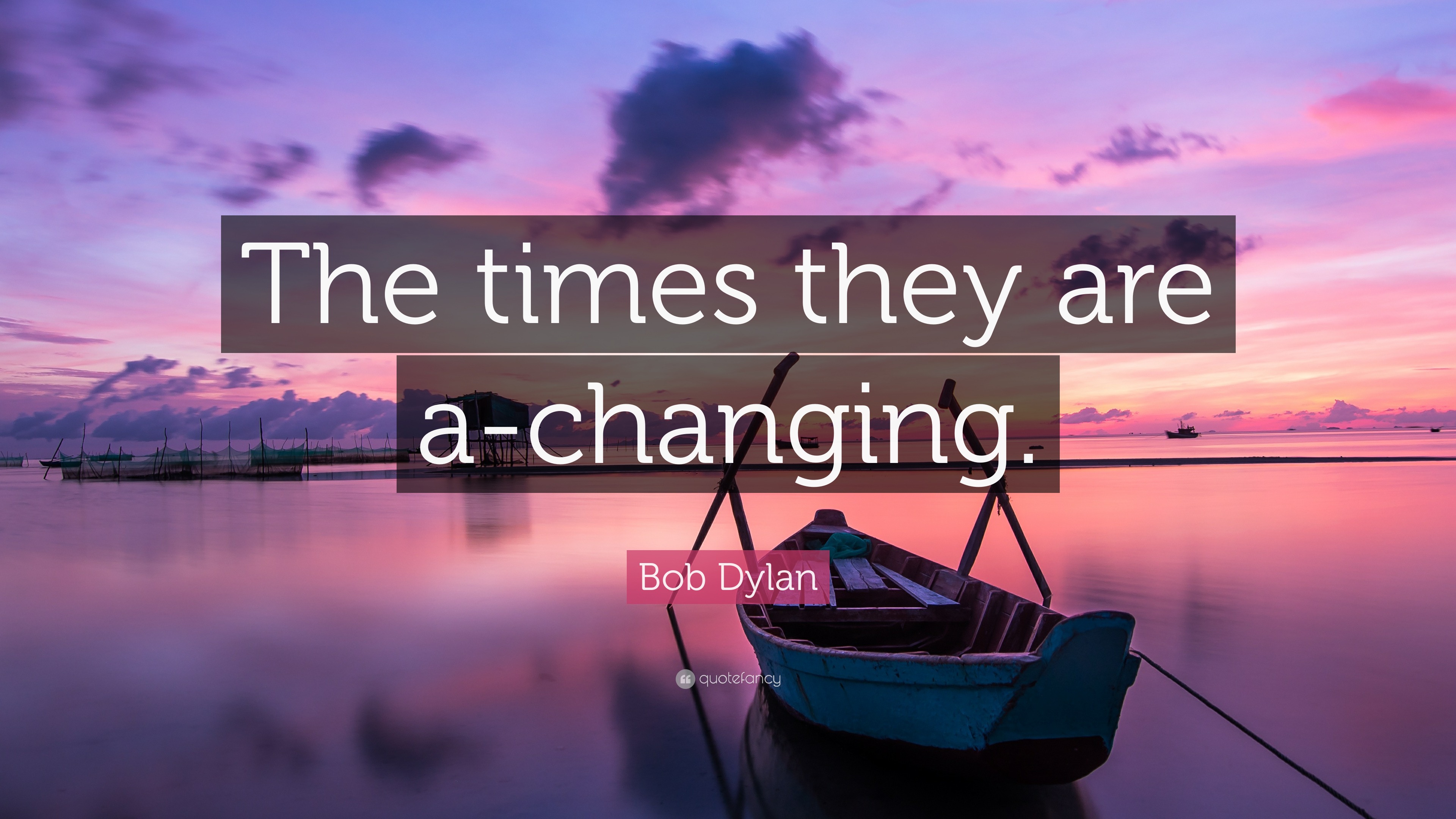A boat on a serene calm lake during a sunset with the bob dylan quote "The times they are a-changing" overlaid.  The image is taken from Quotefancy