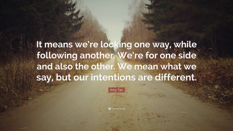 Amy Tan Quote: “It means we’re looking one way, while following another. We’re for one side and also the other. We mean what we say, but our intentions are different.”