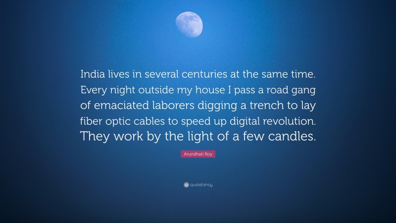 Arundhati Roy Quote: “India lives in several centuries at the same time. Every night outside my house I pass a road gang of emaciated laborers digging a trench to lay fiber optic cables to speed up digital revolution. They work by the light of a few candles.”