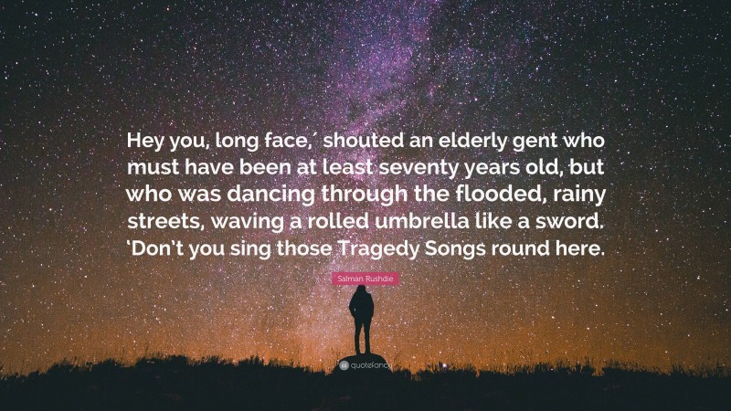 Salman Rushdie Quote: “Hey you, long face,′ shouted an elderly gent who must have been at least seventy years old, but who was dancing through the flooded, rainy streets, waving a rolled umbrella like a sword. ‘Don’t you sing those Tragedy Songs round here.”