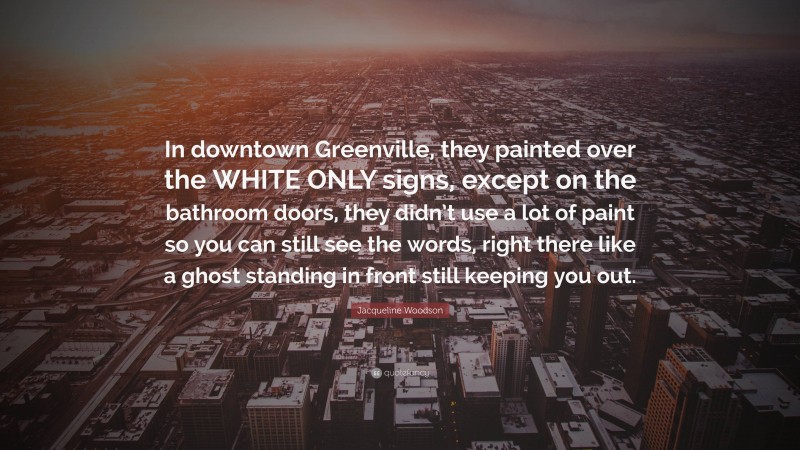 Jacqueline Woodson Quote: “In downtown Greenville, they painted over the WHITE ONLY signs, except on the bathroom doors, they didn’t use a lot of paint so you can still see the words, right there like a ghost standing in front still keeping you out.”