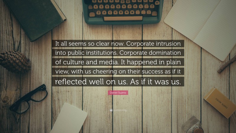 Daniel Suarez Quote: “It all seems so clear now. Corporate intrusion into public institutions. Corporate domination of culture and media. It happened in plain view, with us cheering on their success as if it reflected well on us. As if it was us.”