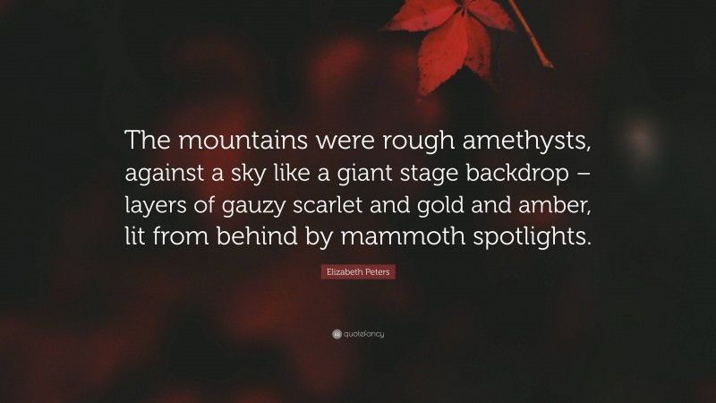 Elizabeth Peters Quote: “The mountains were rough amethysts, against a sky like a giant stage backdrop – layers of gauzy scarlet and gold and amber, lit from behind by mammoth spotlights.”