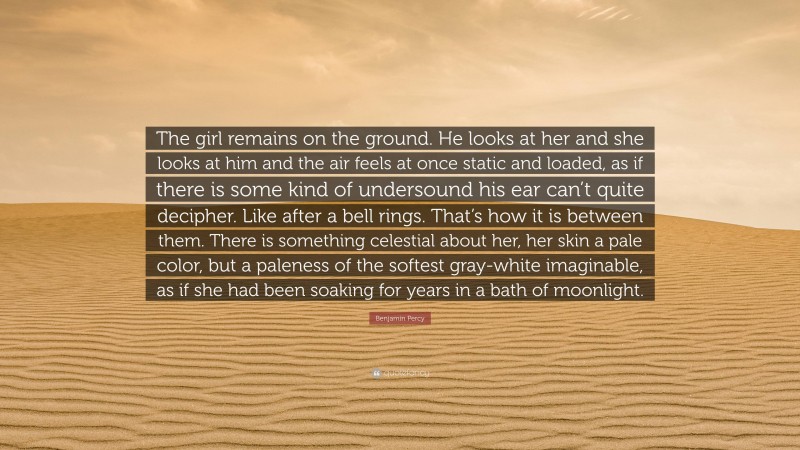 Benjamin Percy Quote: “The girl remains on the ground. He looks at her and she looks at him and the air feels at once static and loaded, as if there is some kind of undersound his ear can’t quite decipher. Like after a bell rings. That’s how it is between them. There is something celestial about her, her skin a pale color, but a paleness of the softest gray-white imaginable, as if she had been soaking for years in a bath of moonlight.”