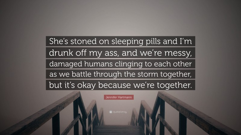 Jennifer Hartmann Quote: “She’s stoned on sleeping pills and I’m drunk off my ass, and we’re messy, damaged humans clinging to each other as we battle through the storm together, but it’s okay because we’re together.”