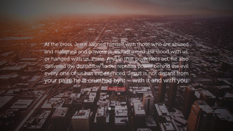 Russell D. Moore Quote: “At the cross, Jesus aligned himself with those who are abused and maligned and powerless and ashamed. He stood with us, or hanged with us, there. And in that powerless act, he also delivered the deathblow to the reptilian power behind the evil every one of us has experienced. Jesus is not distant from your pain; he is crucified by it – with it and with you.”