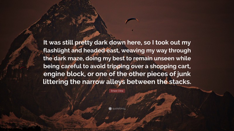 Ernest Cline Quote: “It was still pretty dark down here, so I took out my flashlight and headed east, weaving my way through the dark maze, doing my best to remain unseen while being careful to avoid tripping over a shopping cart, engine block, or one of the other pieces of junk littering the narrow alleys between the stacks.”