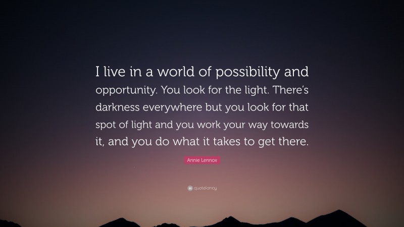 Annie Lennox Quote: “I live in a world of possibility and opportunity. You look for the light. There’s darkness everywhere but you look for that spot of light and you work your way towards it, and you do what it takes to get there.”