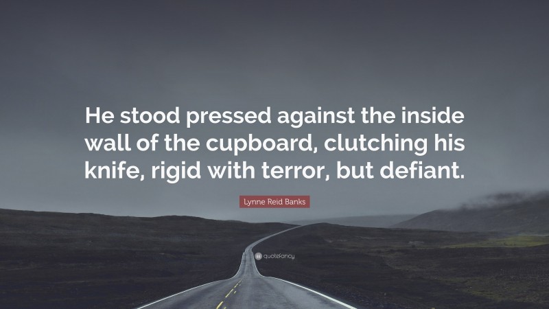 Lynne Reid Banks Quote: “He stood pressed against the inside wall of the cupboard, clutching his knife, rigid with terror, but defiant.”