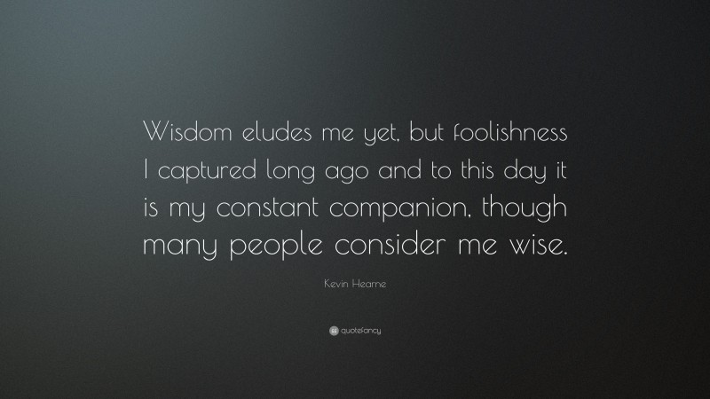 Kevin Hearne Quote: “Wisdom eludes me yet, but foolishness I captured long ago and to this day it is my constant companion, though many people consider me wise.”