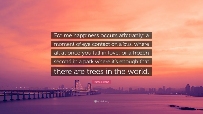 Russell Brand Quote: “For me happiness occurs arbitrarily: a moment of eye contact on a bus, where all at once you fall in love; or a frozen second in a park where it’s enough that there are trees in the world.”